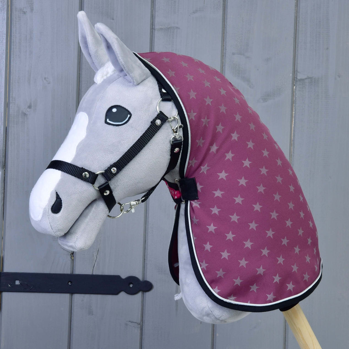 Szürke Hobby Horse ló fekete kötőfékben, rajta a lila csillagmintás istállótakaró fekete szegéssel