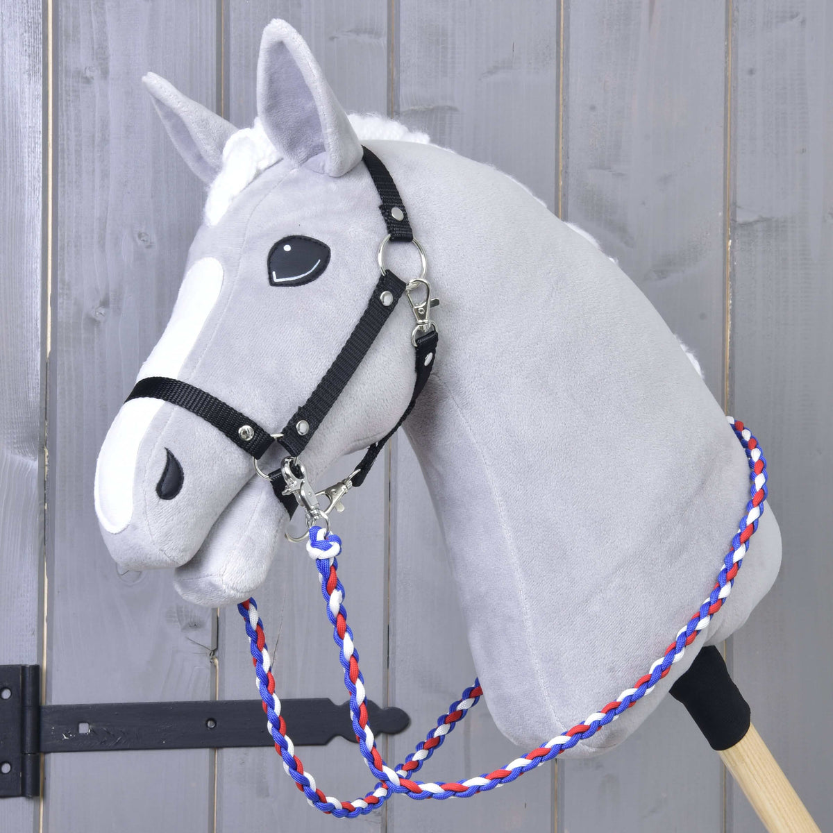 Világosszürke Hobby Horse ló fekete kötőfékben, a nyaka körül a kék-piros-fehér fonott Flag CZ kantárszár