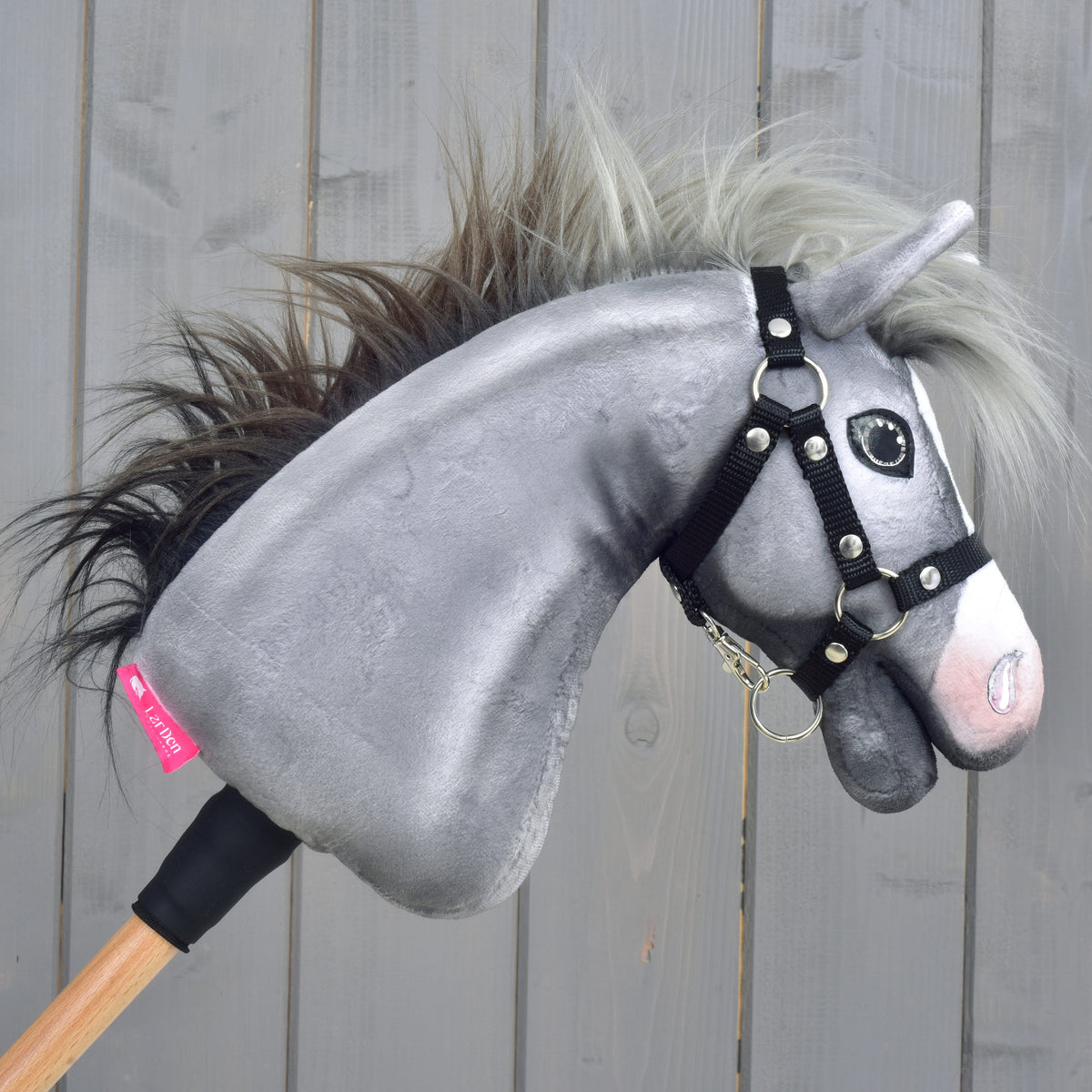 A szürke Hobby Horse ló jobb oldala lobogó sörénnyel, fekete kötőfékkel és rózsaszín LarDen címkével a nyakán