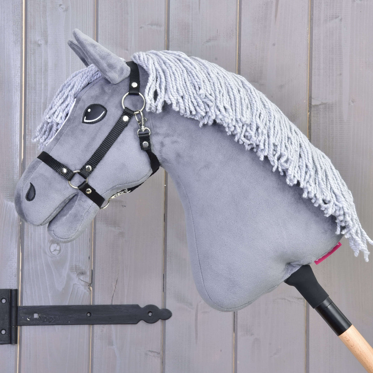 Hobby Horse Grace ló bal profilból, a szürke nyakára omló hosszú halványszürke fonalsörénnyel és fekete kötőfékkel