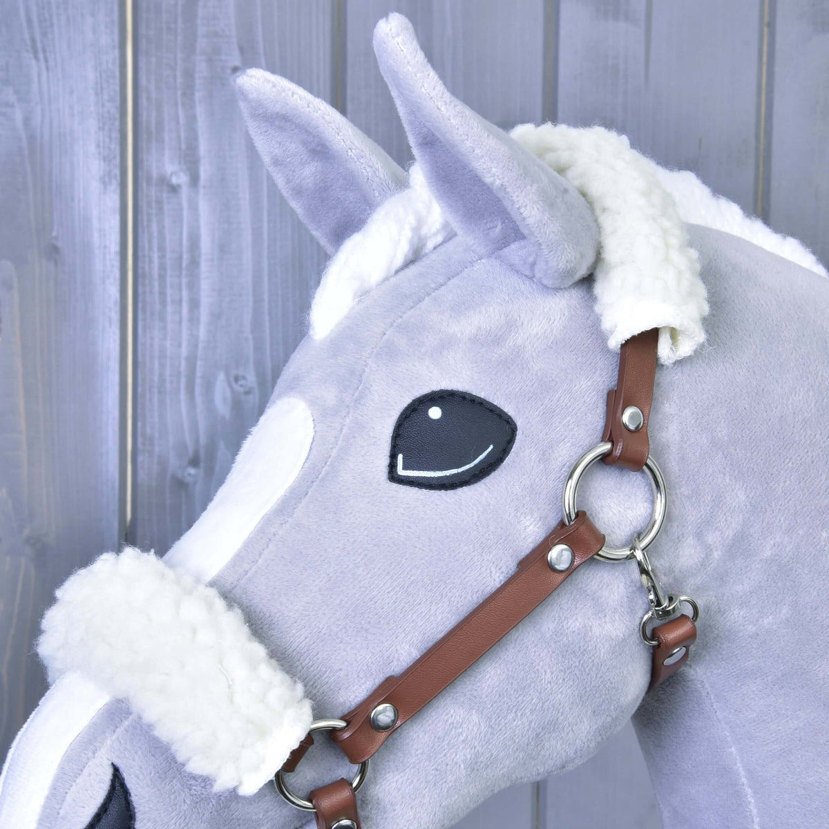 Close-up of the white fur padding and silver cheek ring of the brown leatherette halter on a grey Hobby Horse