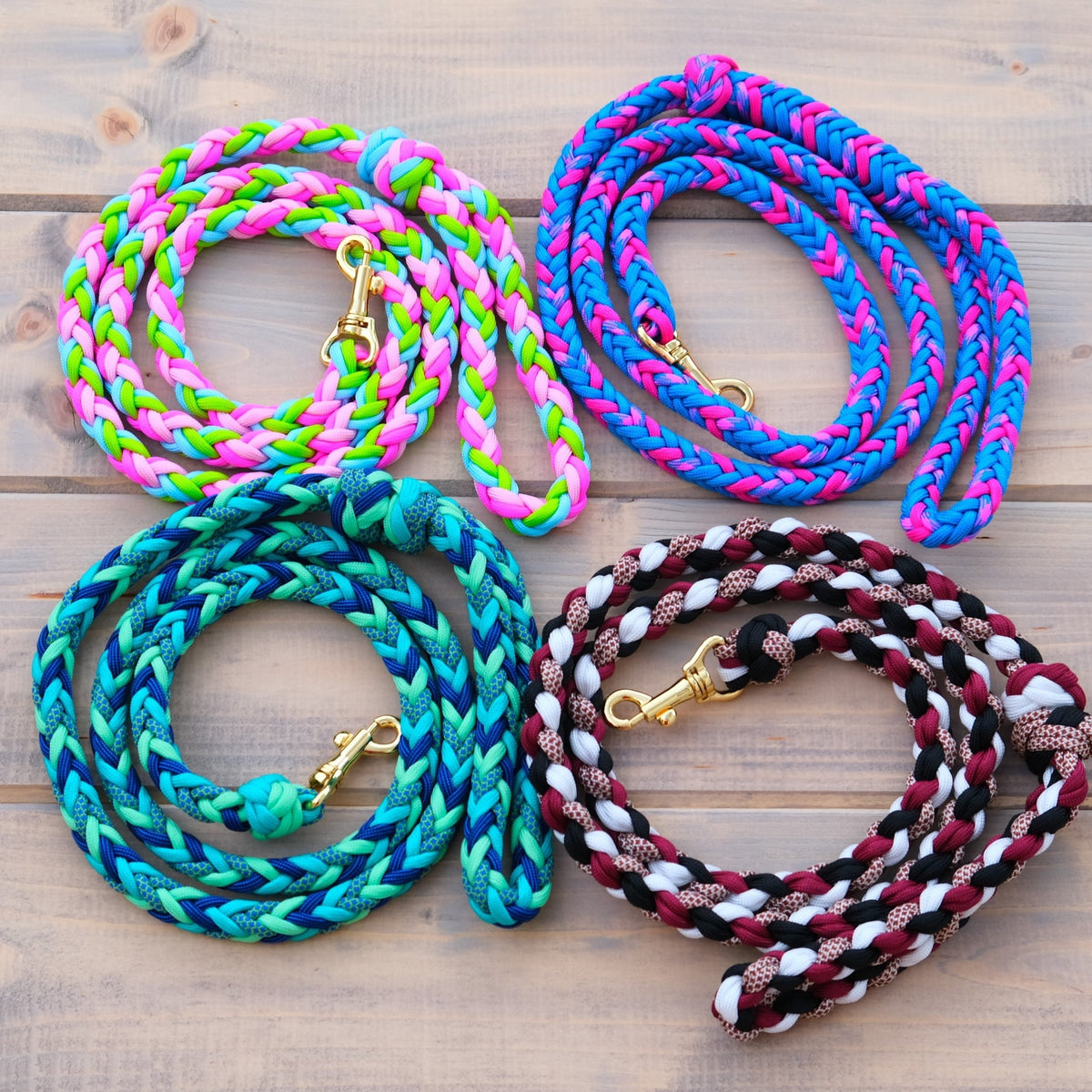 Four braided Hobby Horse lead ropes with brass snap hooks in pink-green, blue-pink, teal and black-white on wooden boards
