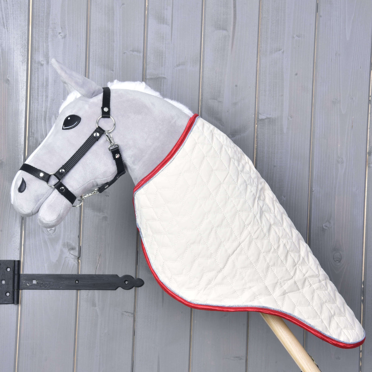 Szürke Hobby Horse ló profilból, a krémszínű steppelt szállítótakaró a nyakát egészen a fabotig befedi