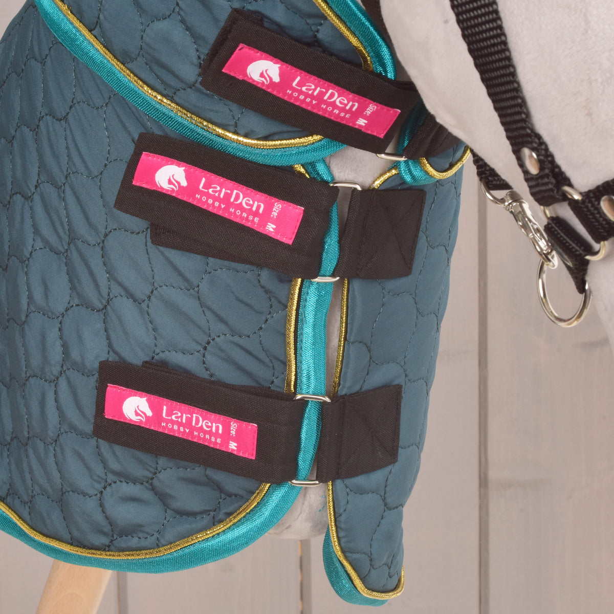 Three black chest straps with pink LarDen labels fastened on the Lagoon blanket worn by a grey Hobby Horse in a black halter