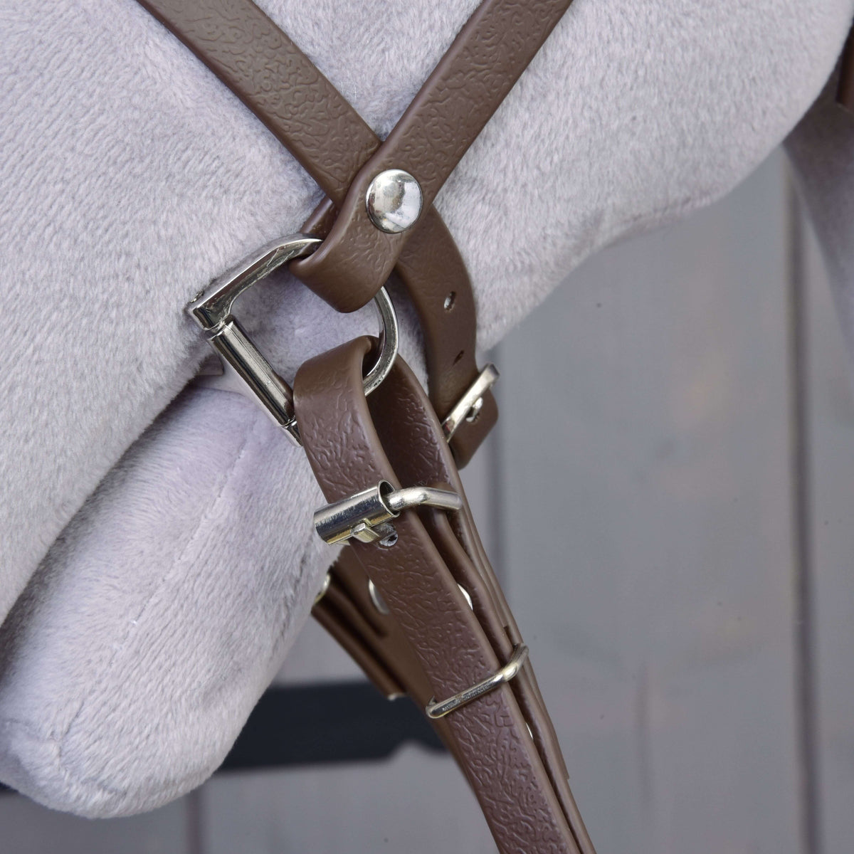 A barna műbőr orrszíj, a zablakarika és a szárcsatlakozó közelről ezüst csatokkal egy szürke Hobby Horse lovon