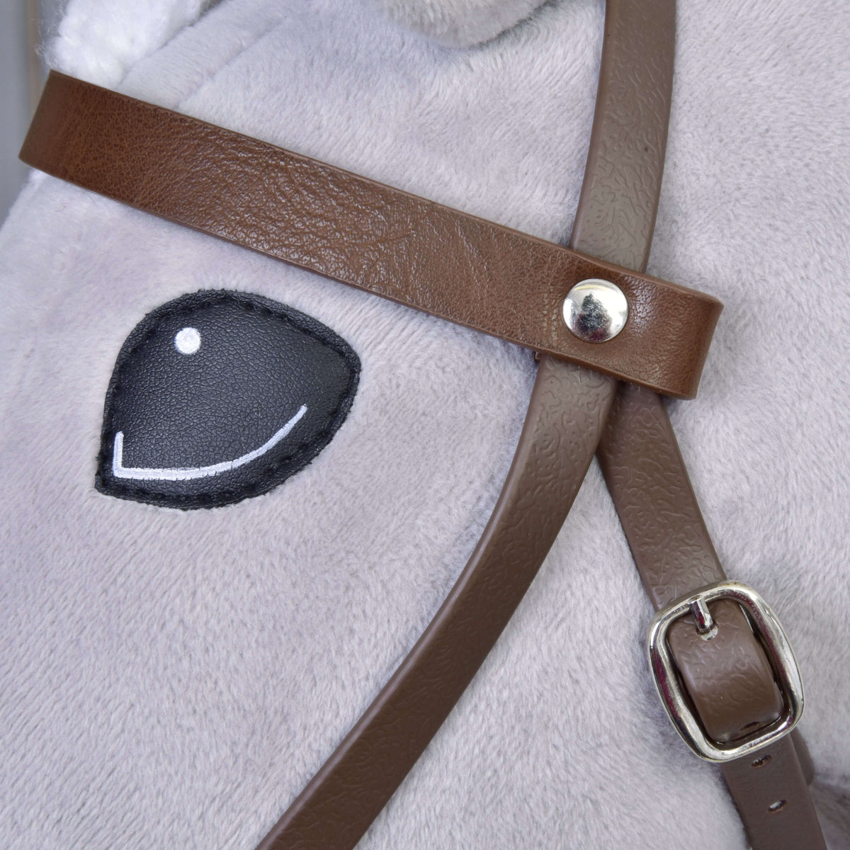A barna műbőr homlokszíj közelről ezüst szegeccsel és pofaszíjcsattal egy Hobby Horse ló szeme mellett