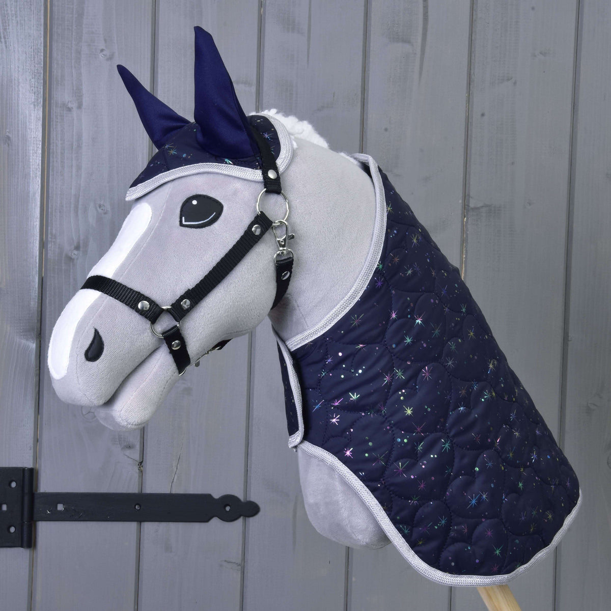Szürke plüss Hobby Horse ló fekete kötőfékkel, rajta a sötétkék Magic szett takarója és fülvédője csillogó csillagokkal