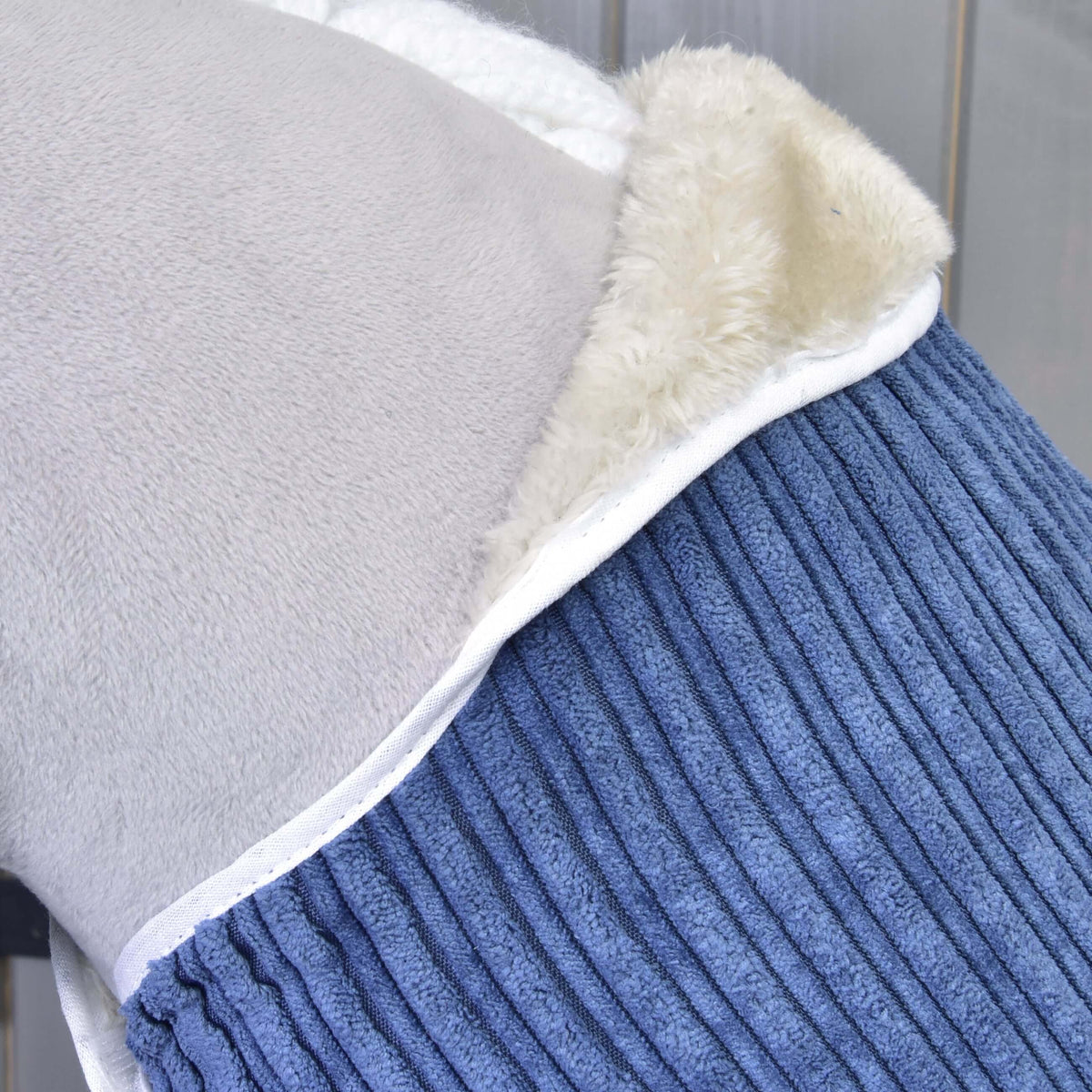 Close-up of the Set Manchester Plum blanket neckline with cream fleece lining and white piping on a grey Hobby Horse
