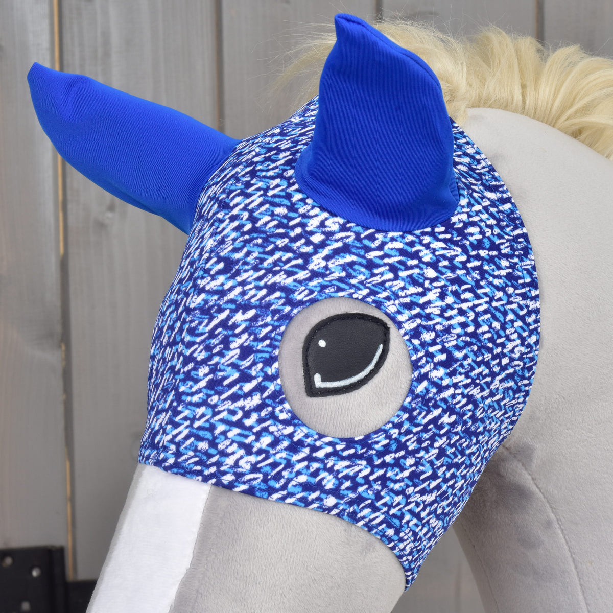 Közeli kép a See maszkról egy szürke Hobby Horse lovon, a hímzett szemet a pettyes kék anyag keretezi