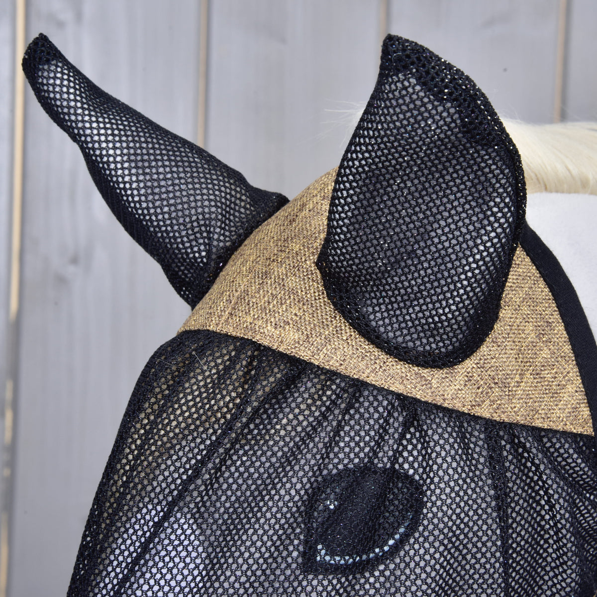 Close-up of the mesh ear covers and the beige woven brow panel of the Mona fly mask, the eye visible under the mesh