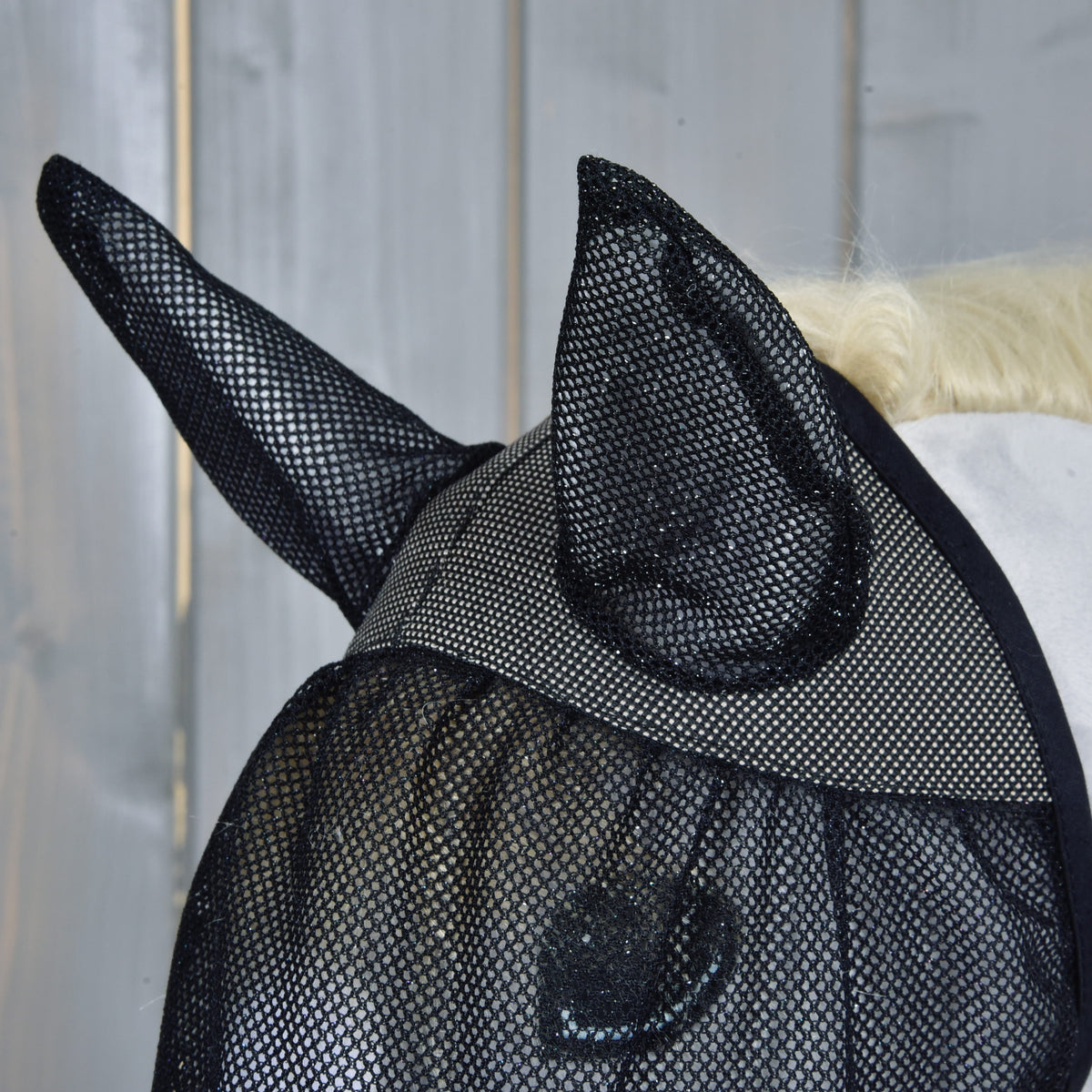 A légymaszk oldalról, felálló hálós fülekkel és finom fekete hálóval egy világosszürke Hobby Horse ló szeme fölött