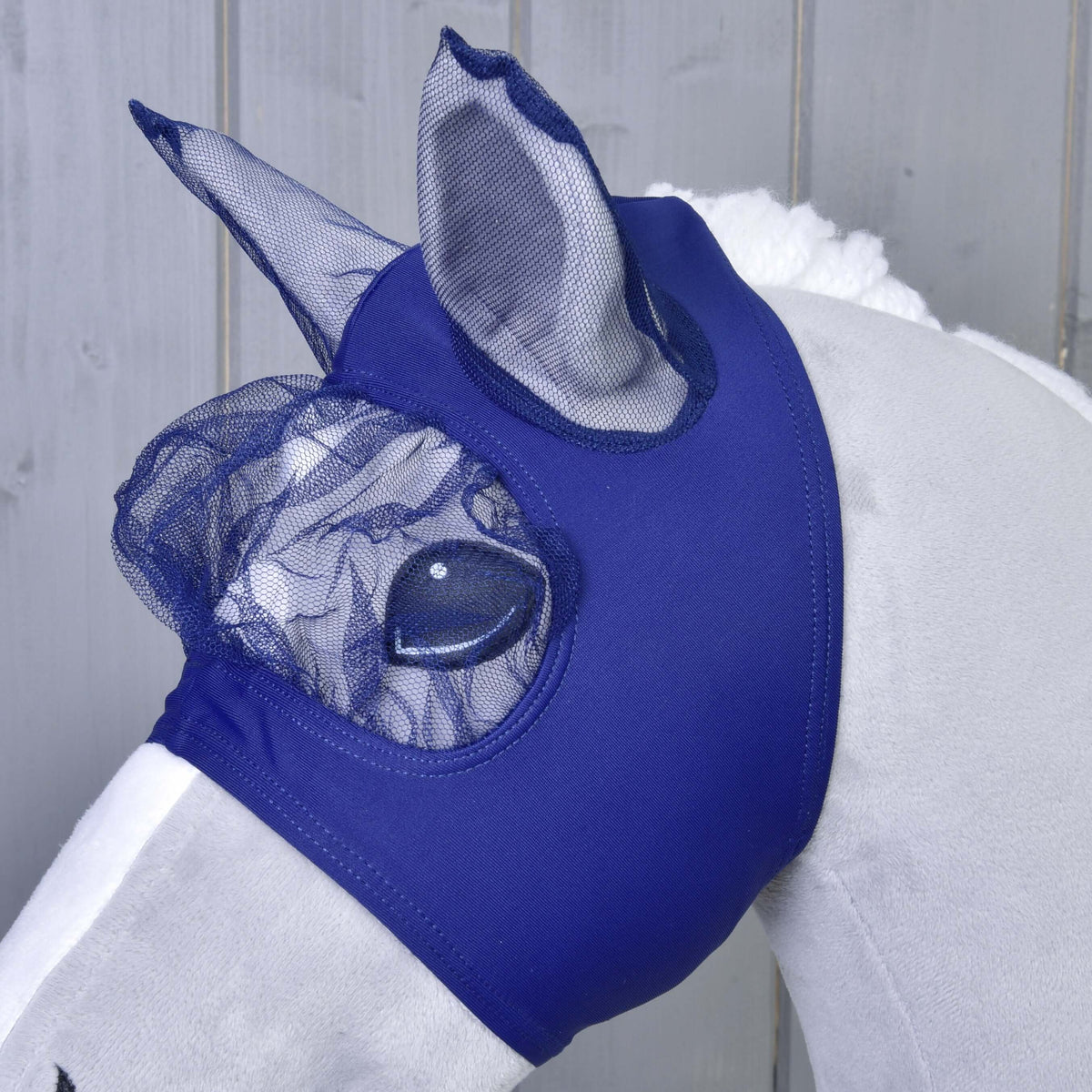 Close-up of the navy net eye cover and mesh ears of the royal blue fly mask on a grey Hobby Horse