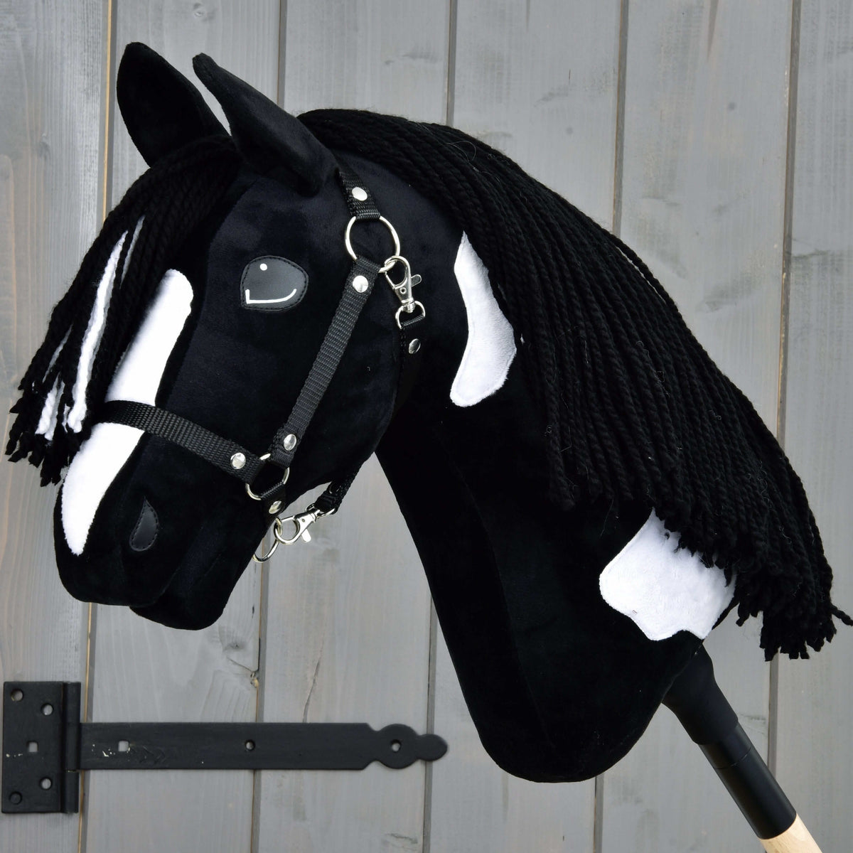 LarDen Hobby Horse Merlin fekete kötőfékkel: fekete plüss fehér hókával és foltokkal, hosszú fekete fonalsörénnyel