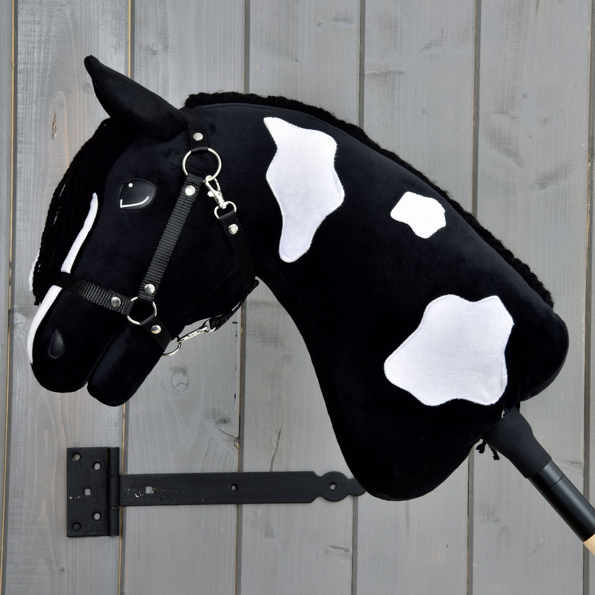 Hobby Horse Merlin fekete kötőfékkel, a fekete nyakán három fehér folt, a sörény a túloldalon