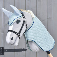 Grey Hobby Horse in a black halter wearing the Set Mint: pale blue quilted blanket and ear bonnet with navy piping