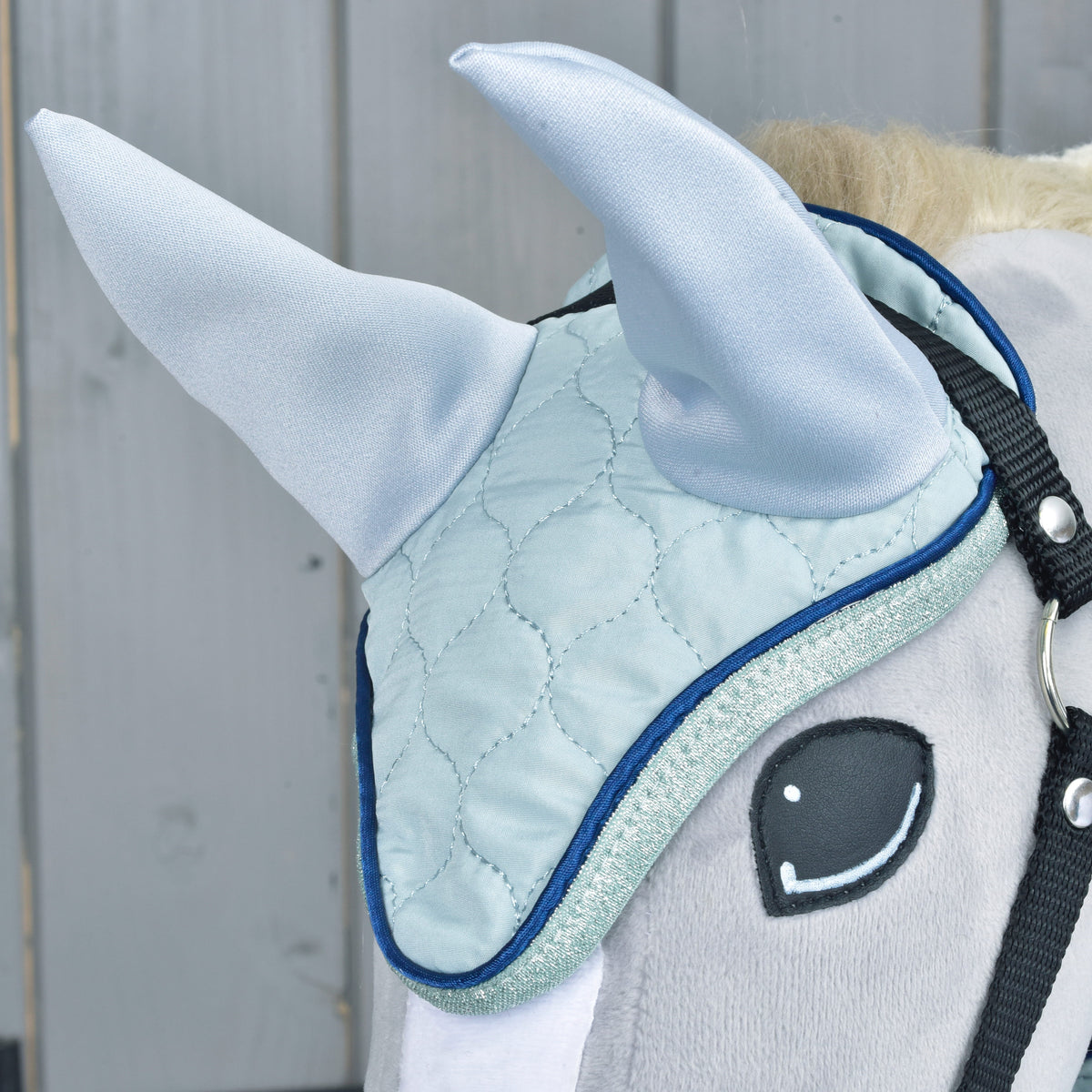 Close-up of the Set Mint ear bonnet on a grey Hobby Horse: pale blue quilting and ears, navy piping and glitter trim