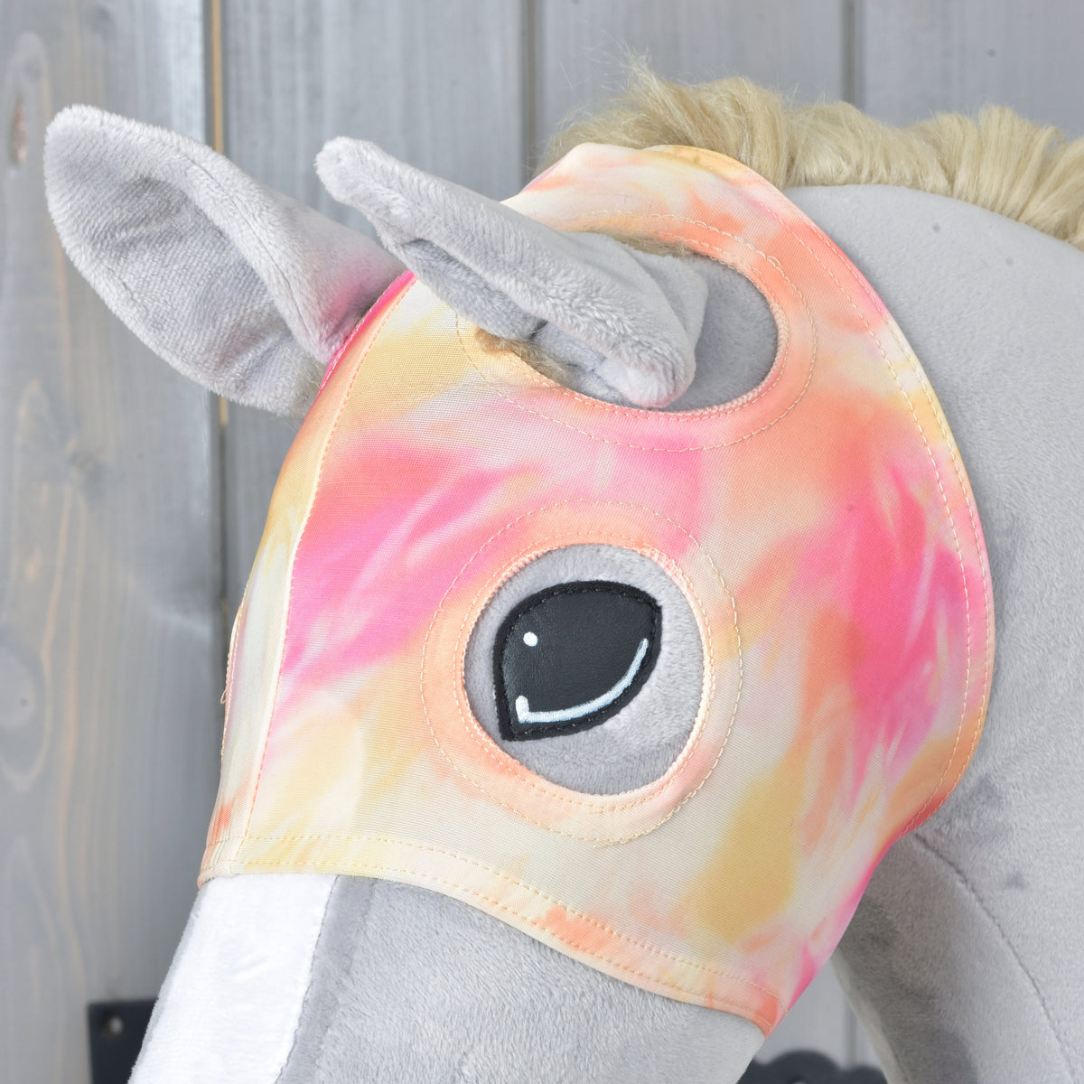 Close-up of the Mirage mask on a grey Hobby Horse, the plush ears poking through and stitched edges around the eye opening