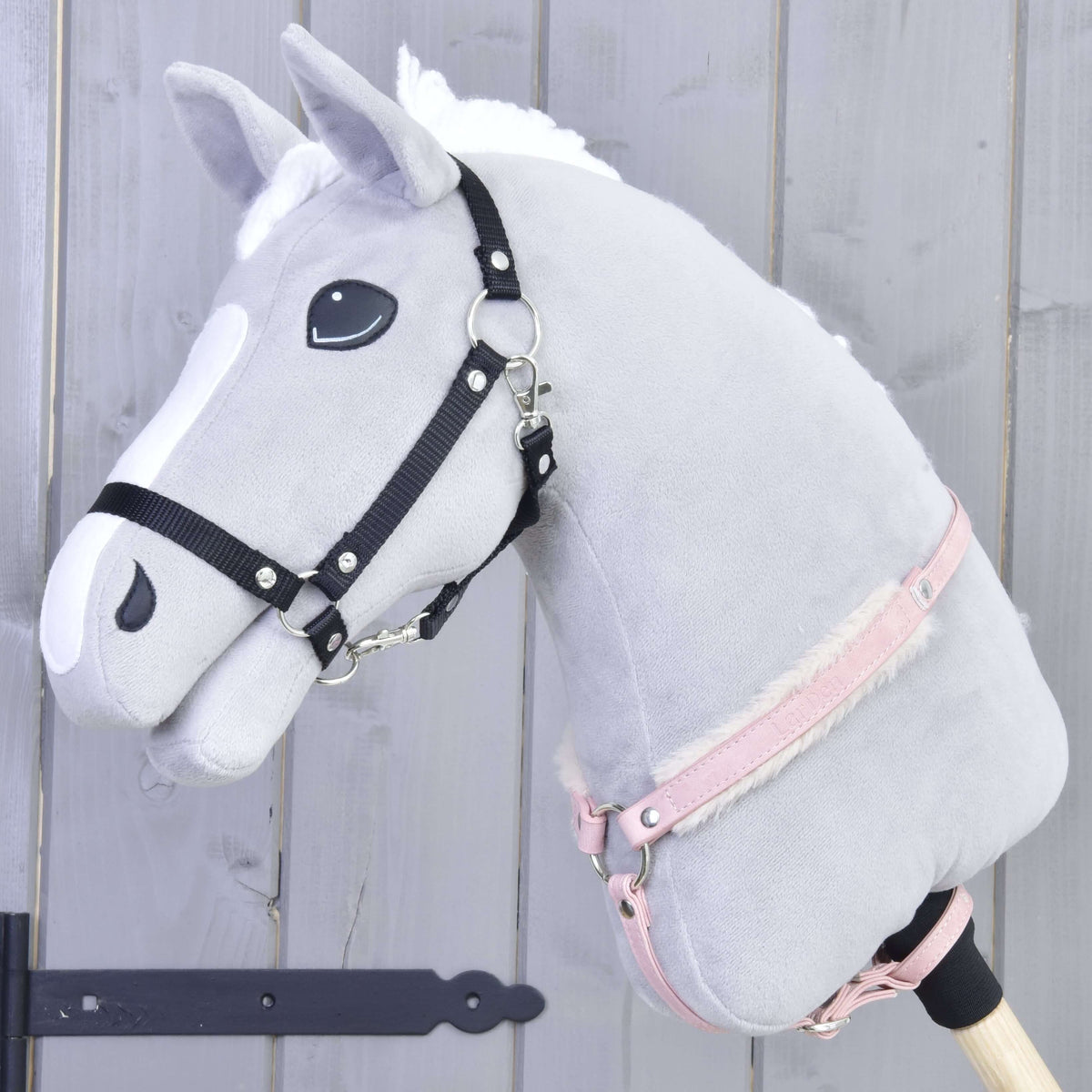 Fekete kötőfékes szürke Hobby Horse ló, a nyaka körül a rózsaszín, szőrmés műbőr szügyelővel