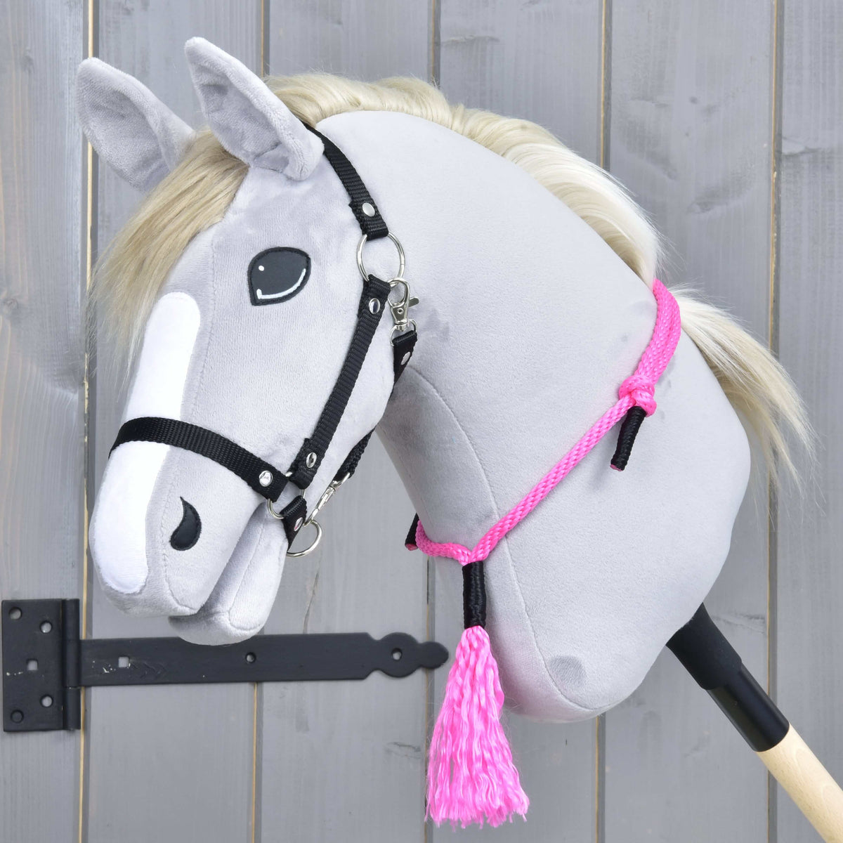 Grey Hobby Horse with a cream mane and black halter wearing Cordeo Pink Festive around its neck, with the pink tassel