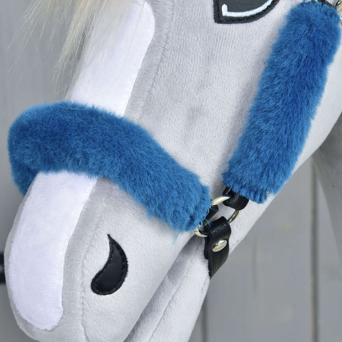 Close-up of the fur-covered noseband over the white blaze, fastened with a black leatherette strap and silver rivet