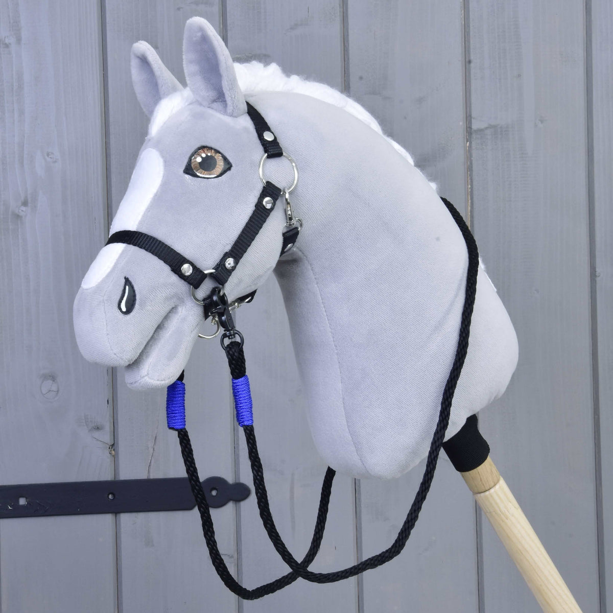 Szürke plüss Hobby Horse ló fekete kötőfékkel és az álla alá csatolt fekete, kék tekerésű kötél kantárszárral