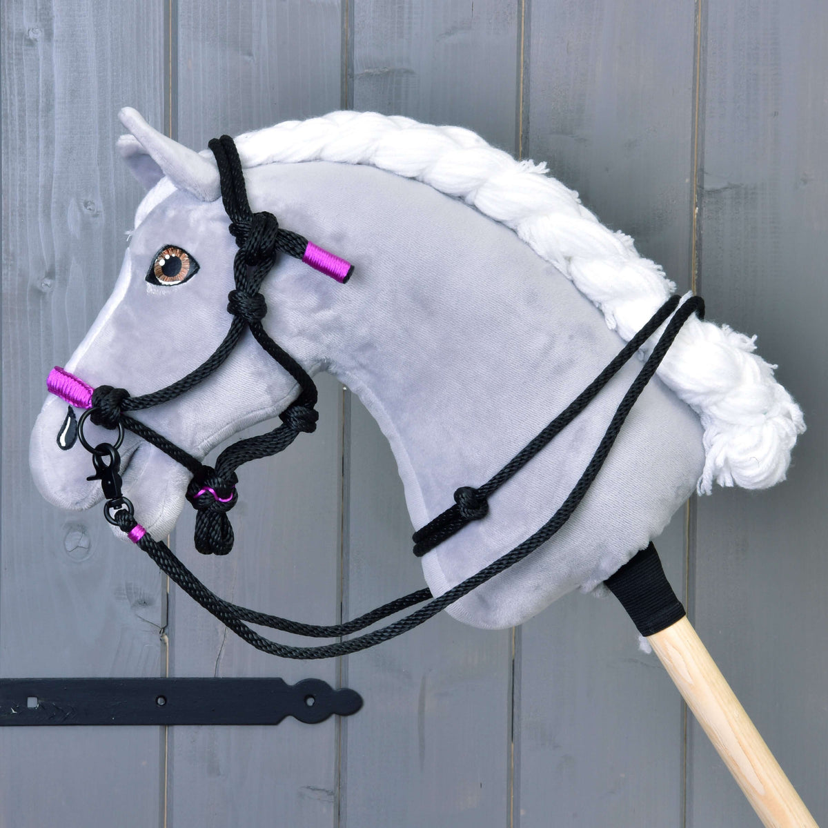 Szürke plüss Hobby Horse ló fonott fehér sörénnyel, rajta a fekete-ibolyalila csomózott kötőfék és fekete kötél kantárszár