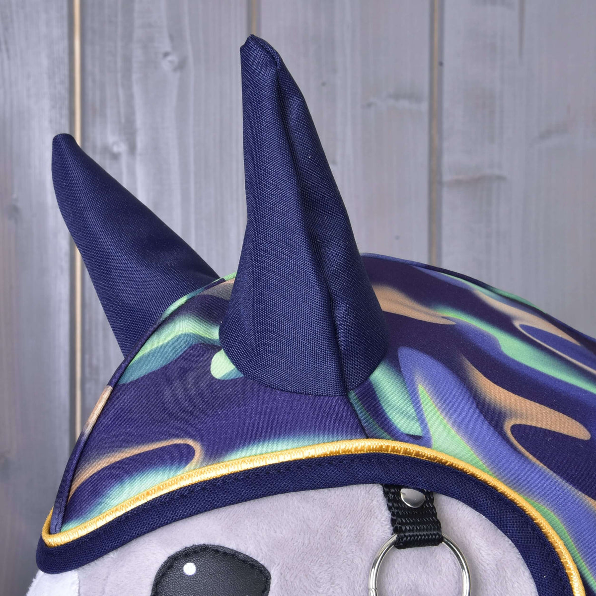 A szivárványos Hobby Horse esőtakaró sötétkék fültakarói és hullámos menta, orgonalila és bézs mintája sárga paszpóllal, közelről