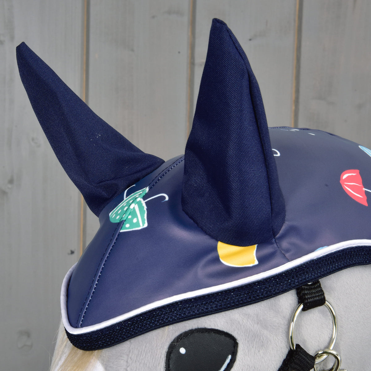 Close-up of the navy fabric ears on the raincoat hood with umbrella print and white piping over the eye