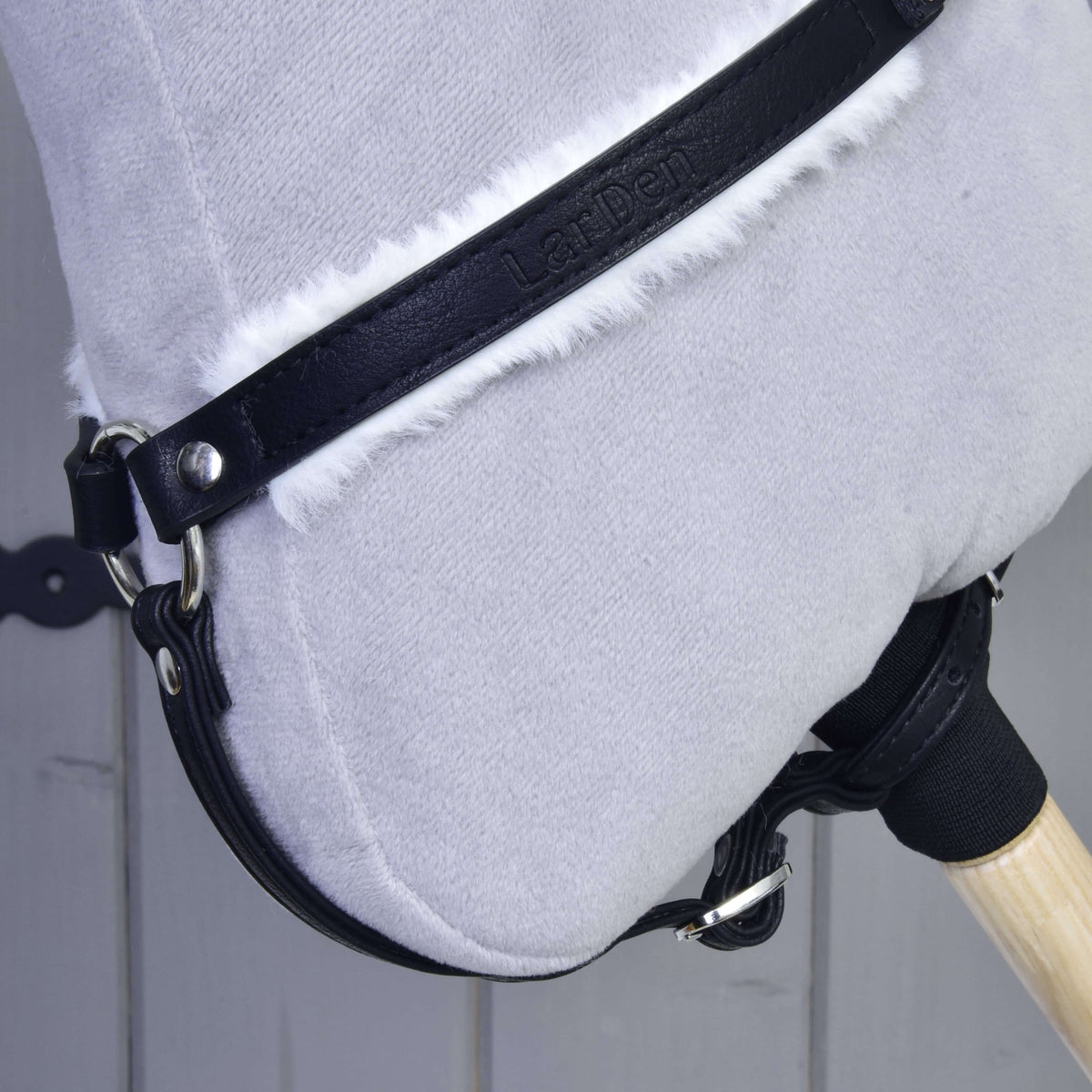 Close-up of the breastgirth with embossed LarDen logo and white fur, buckled around the neck and stick