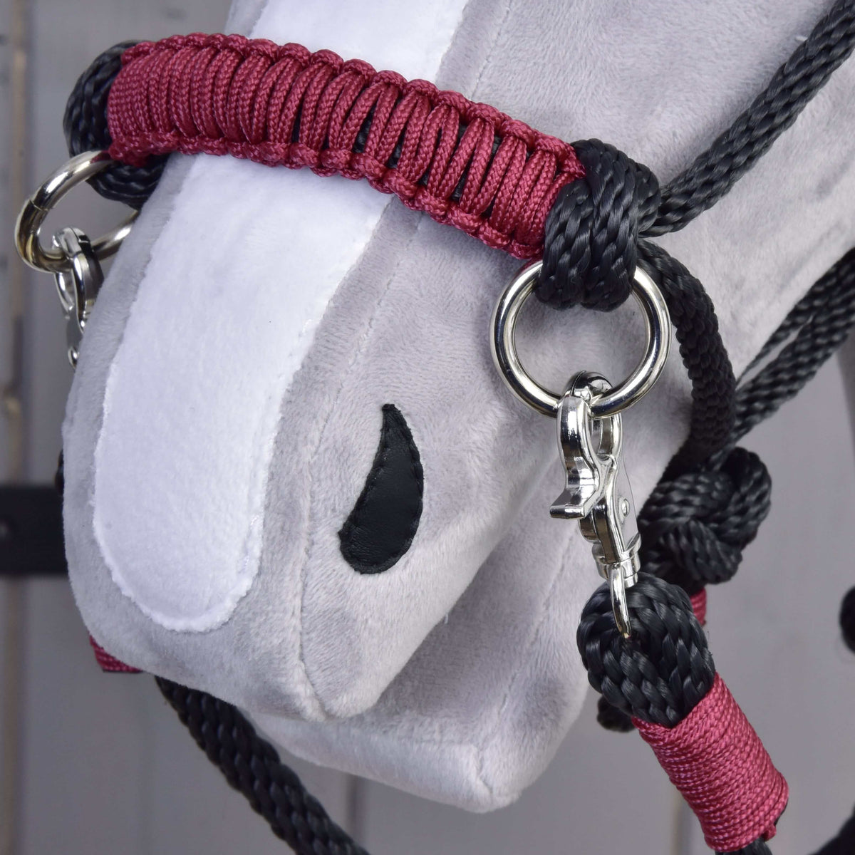 Close-up of the maroon braided noseband of the Hobby Horse Rope set Maroon with black rope, silver ring and snap hook