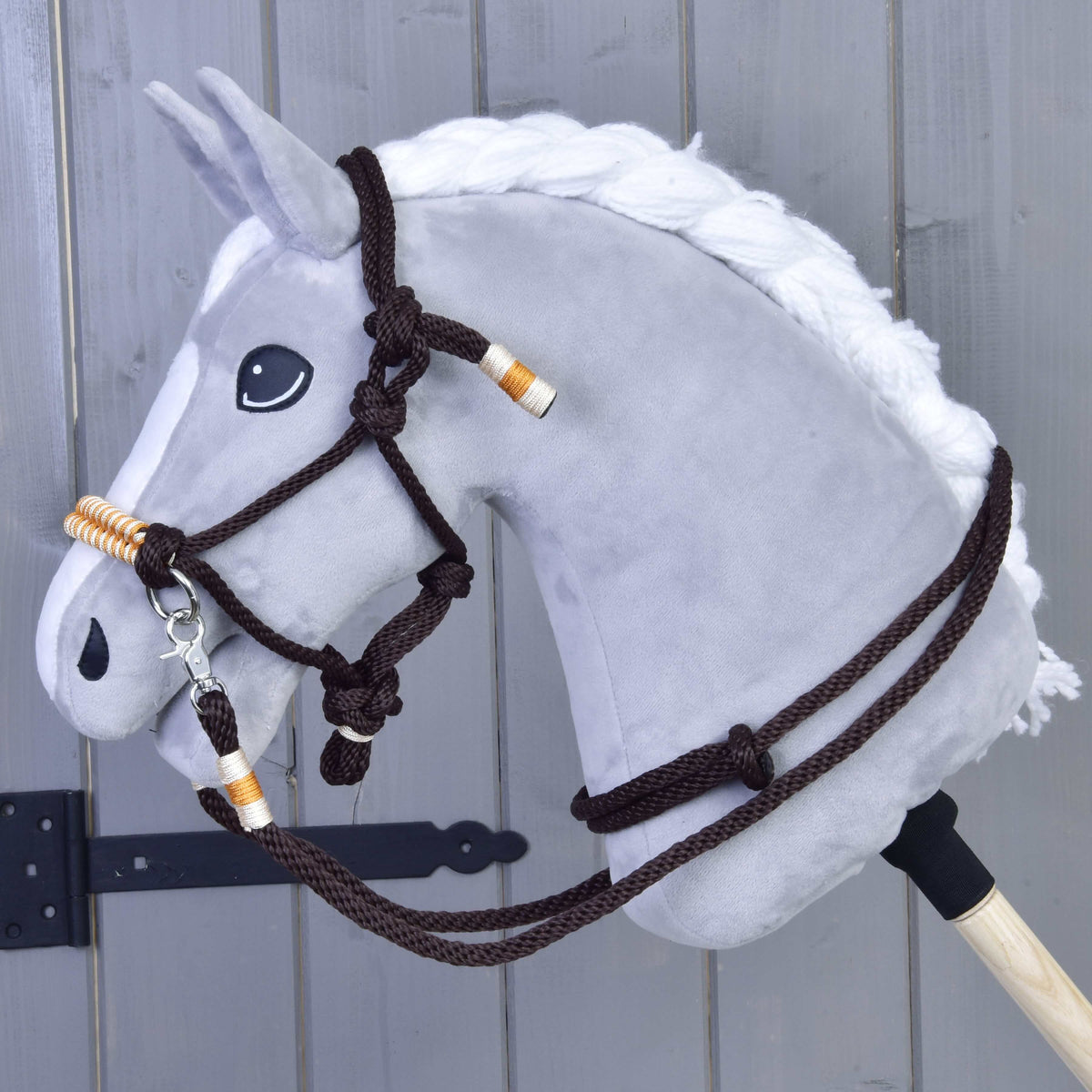 Szürke Hobby Horse ló fonott fehér sörénnyel, rajta a narancssárga kötélszett: sötétbarna csomózott kötőfék és kantárszár narancssárga tekeréssel