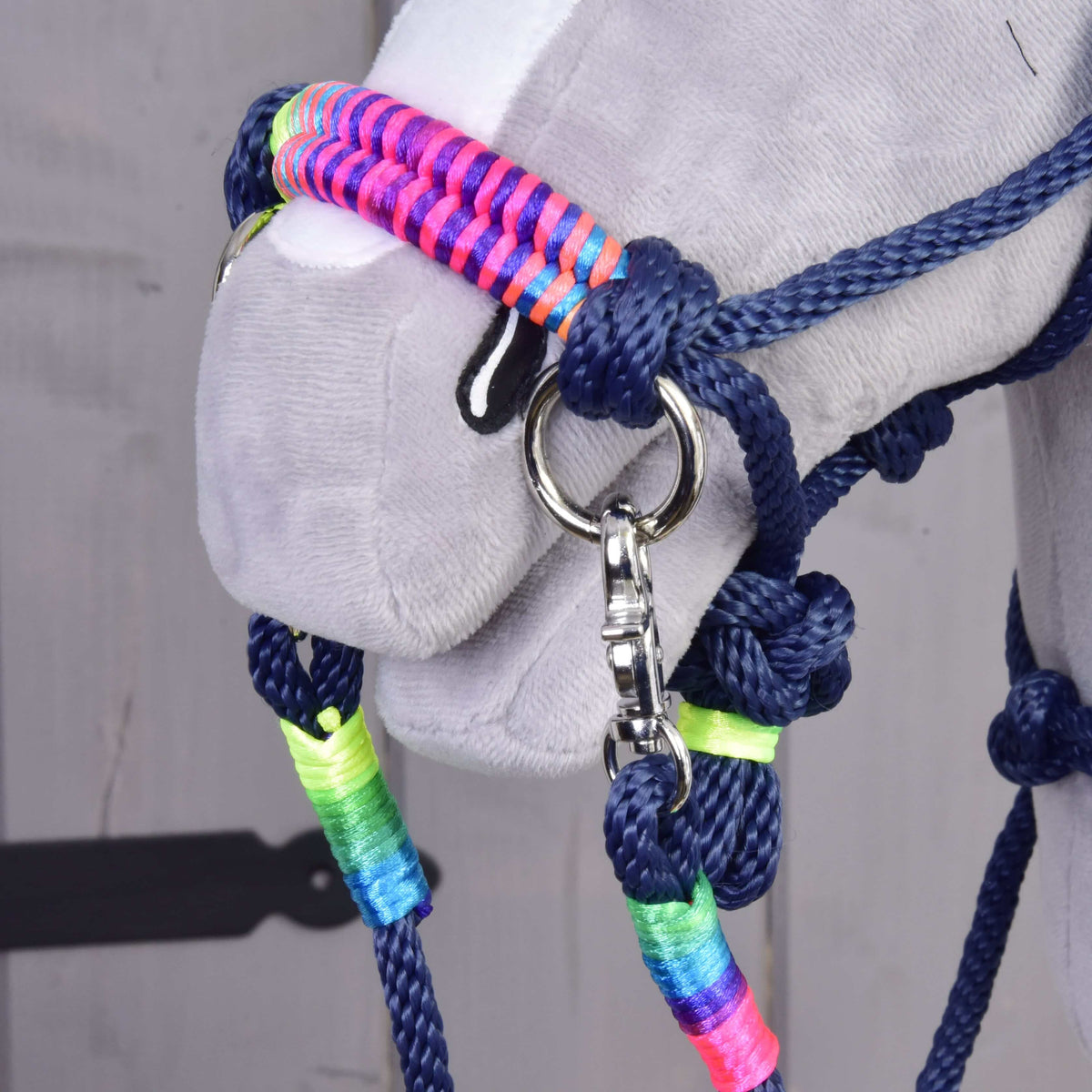Close-up of the Hobby Horse Rope set Rosemary noseband in neon pink, purple and blue with rainbow wraps on the reins