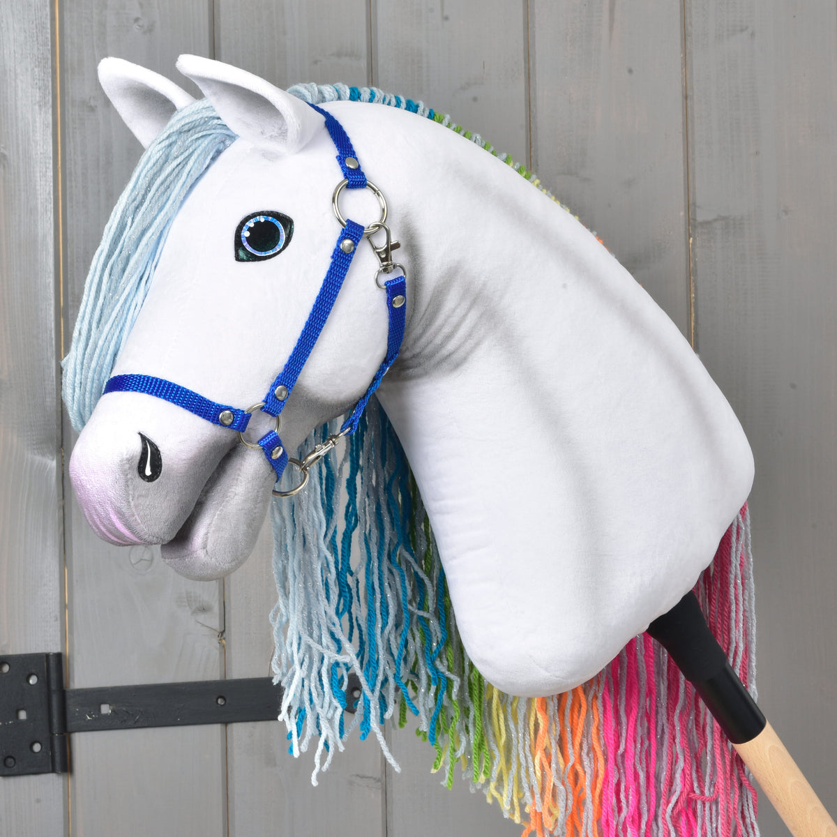 Hobby Horse Rainbow in left profile, mane on the far side with pink, orange and green yarn ends showing below the neck