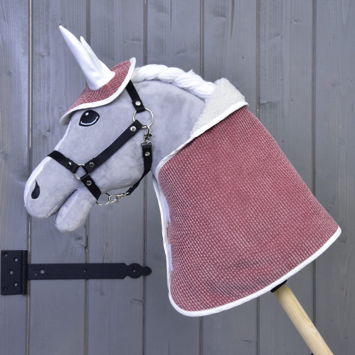 Szürke plüss Hobby Horse ló fekete kötőfékkel, a fáradt rózsaszín Manchester Tea Rose szett takarójában és fülvédőjében