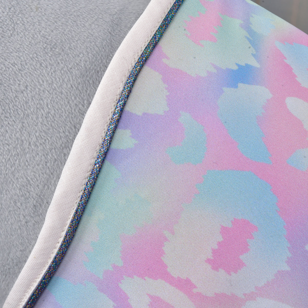Detail of the pastel pink and blue leopard print Hobby Horse blanket with white binding and shimmering cord trim