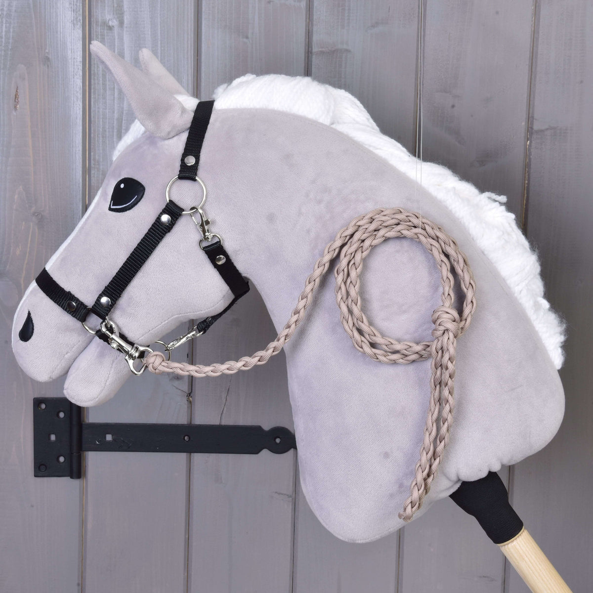 Taupe braided lead rope clipped to the black halter of a light grey Hobby Horse with white mane