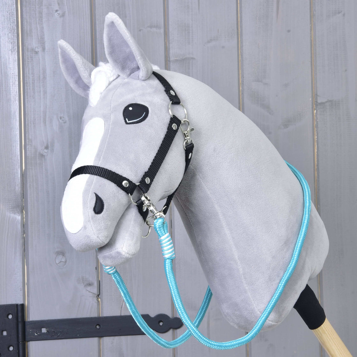 Világosszürke Hobby Horse ló fekete kötőfékben, a türkiz Atlantis kantárszár a nyaka köré vetve