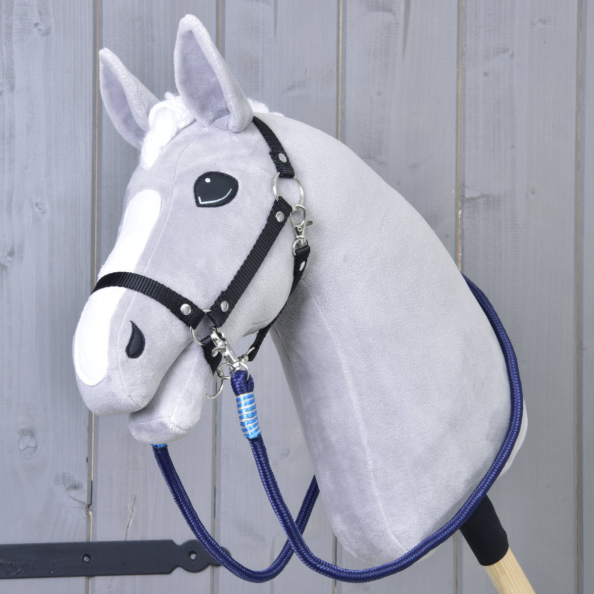 Light grey Hobby Horse in a black halter wearing the navy Reins Blues with light blue wraps around its neck
