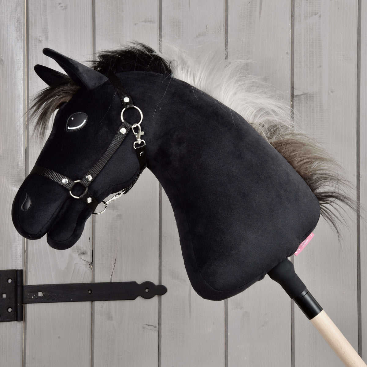 Hobby Horse Bond fekete kötőfékkel teljes profilban a fabotján, az ezüstszürke sörény a fekete nyakra omlik