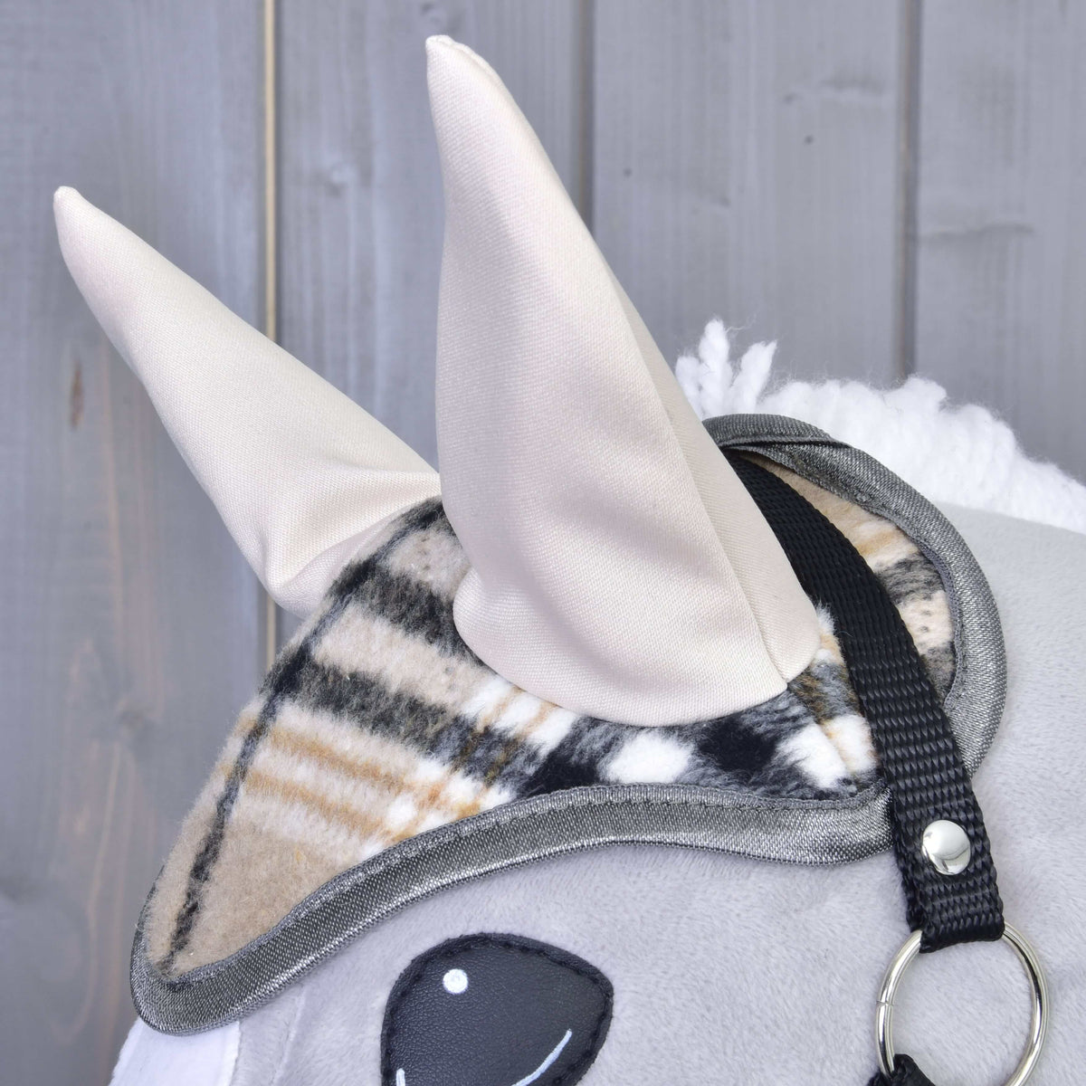 Side close-up of the check ear bonnet with tall cream ears and grey binding beside the black halter strap