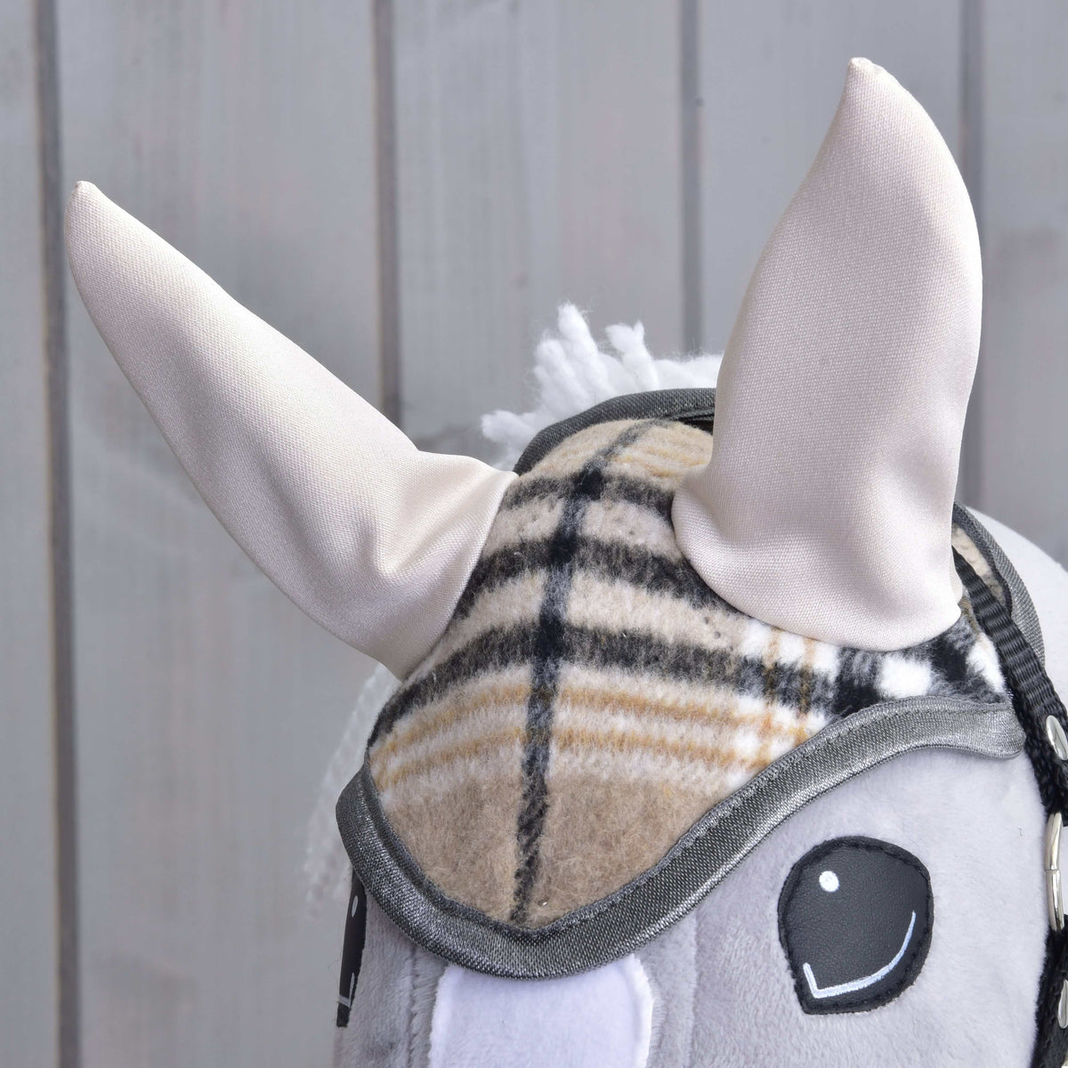 Front close-up of the beige, black and white check ear bonnet with cream ears above the black eyes
