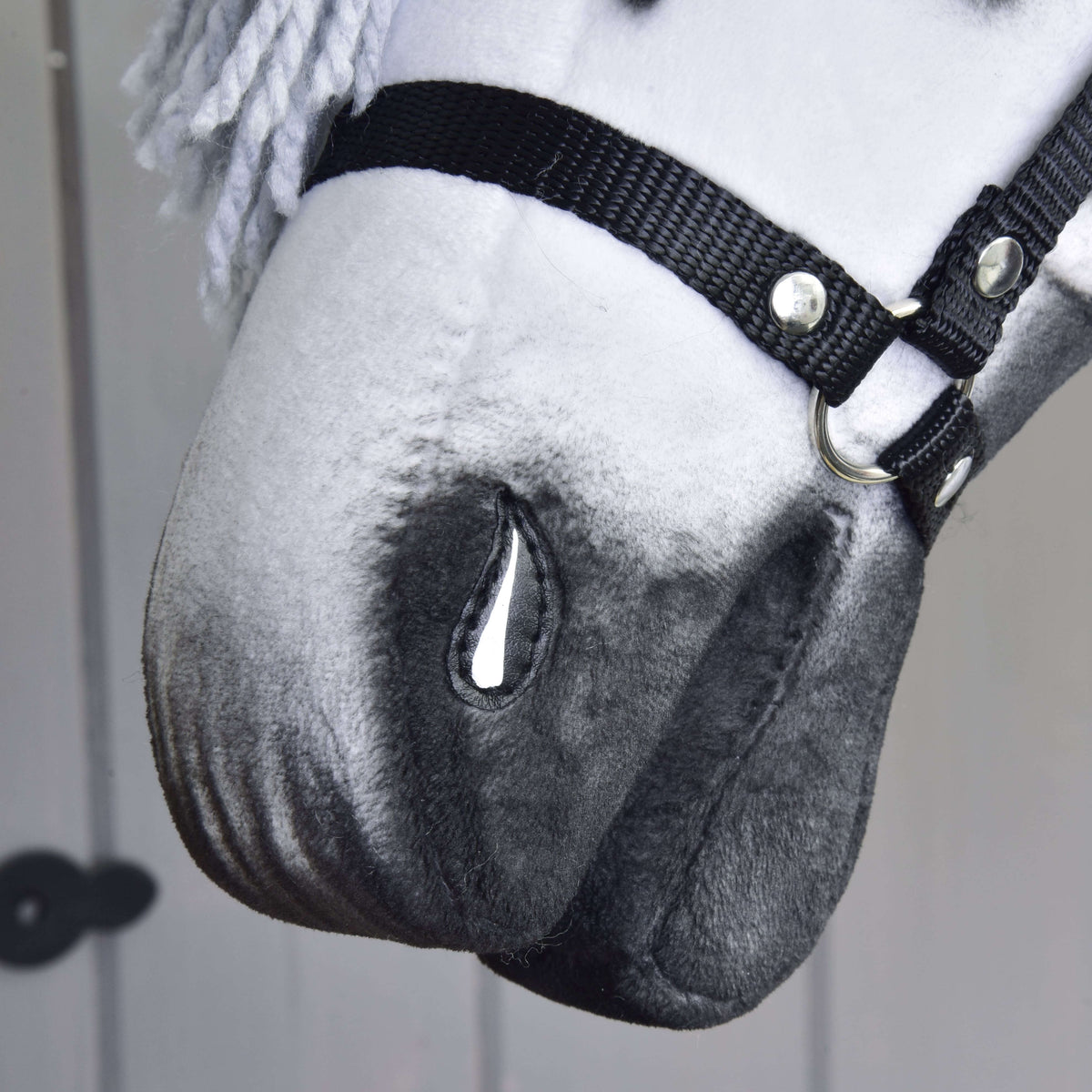A Hobby Horse Chantal ló szürkén árnyalt orra közelről, festett orrlyukkal és a fekete kötőfék orrszíjával