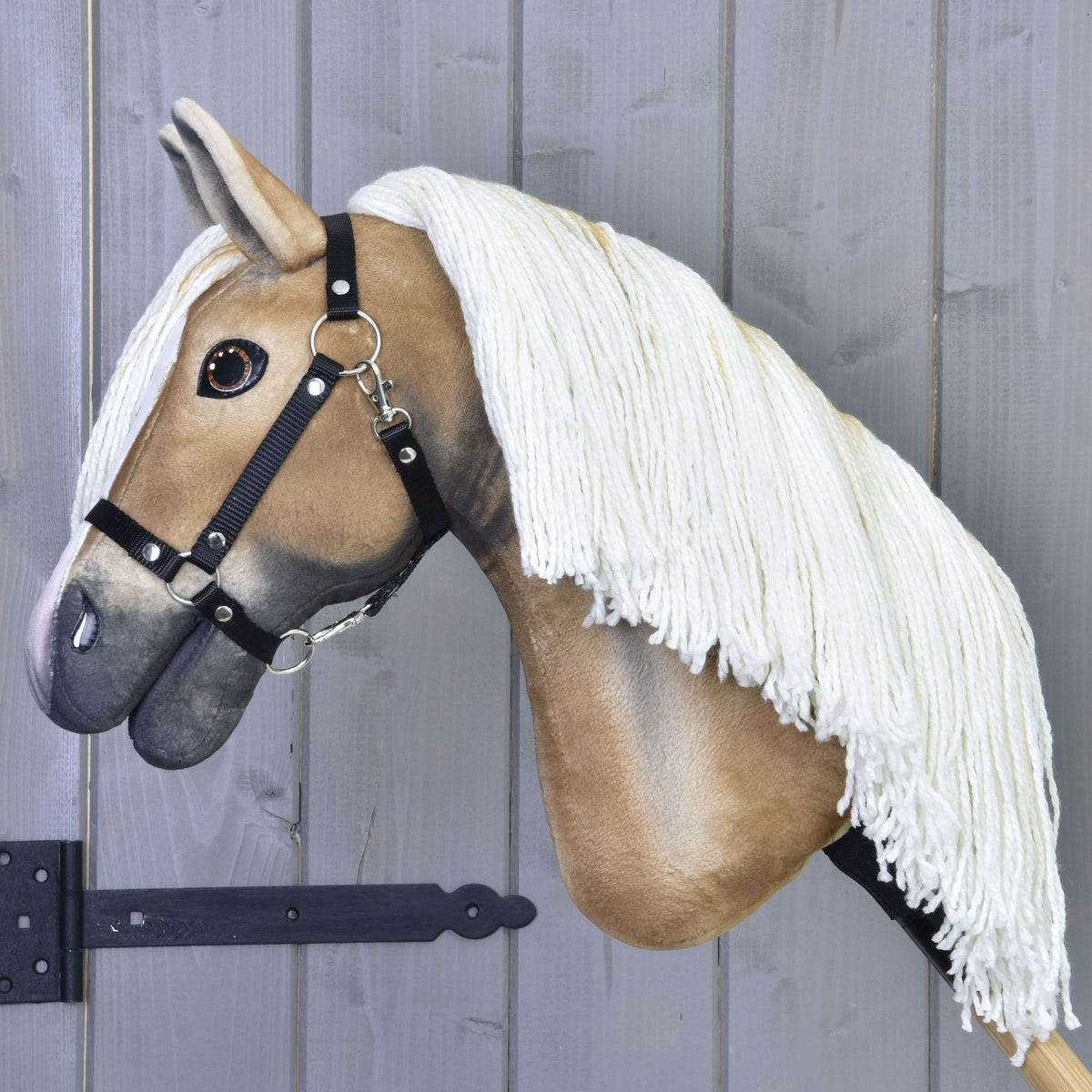 Side view of the golden tan Hobby Horse with a long cream yarn mane and black halter on a wooden stick