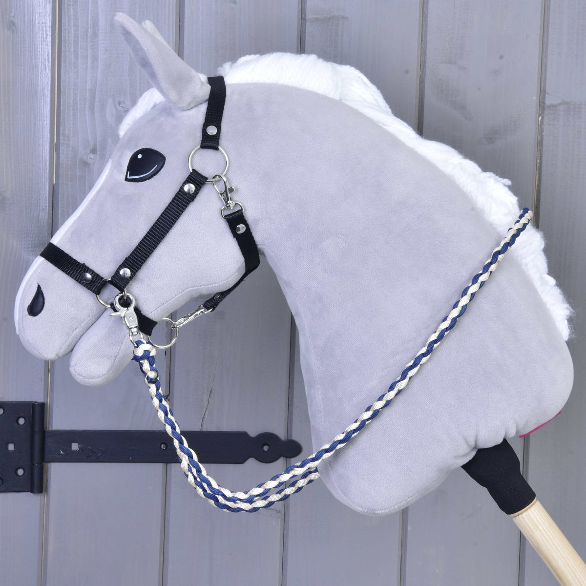 Grey plush Hobby Horse with a black halter and navy and cream braided Cremo/Blue reins hanging along its neck