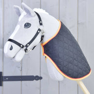 Grey Hobby Horse with a black halter wearing the black quilted blanket with gold and red trim on its neck