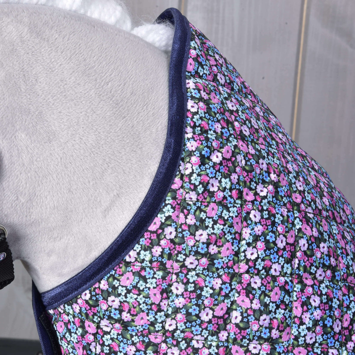 Close-up of the flower print blanket at the neckline of a grey Hobby Horse, quilted fabric edged in navy satin binding