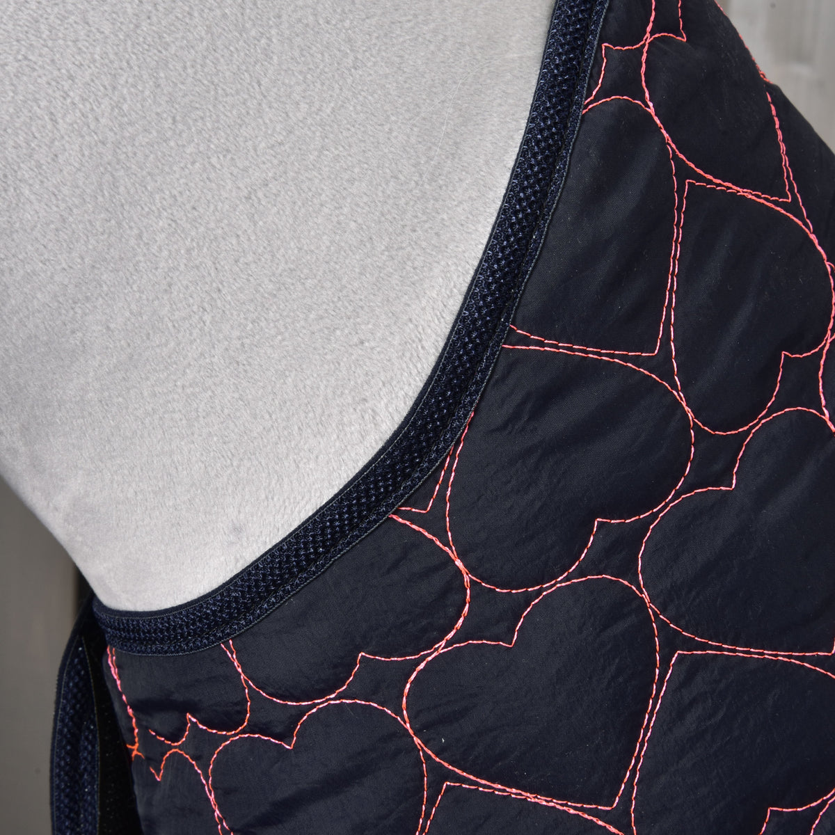 Close-up of the Blanket Pink Heart at the neck: hearts quilted in bright pink thread and navy binding on grey plush