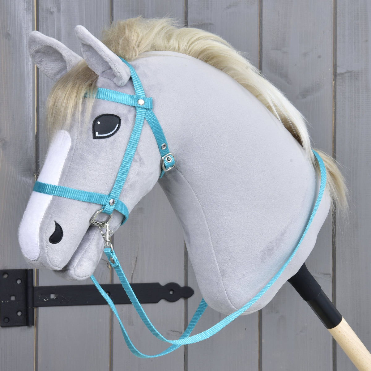 Hobby Horse kantár szárral, hevederből, türkiz, a LarDen kollekciójából, egy szőke sörényű világosszürke plüssfejen