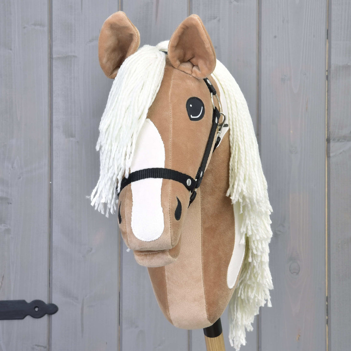 Front view of Hobby Horse Fury with a wide white blaze, cream yarn forelock and black halter