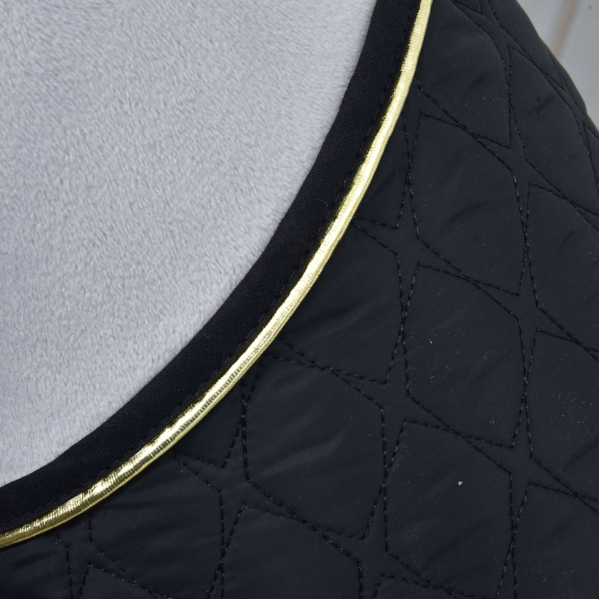 Close-up of the star-shaped quilting on the black blanket with gold piping along the neckline against grey plush